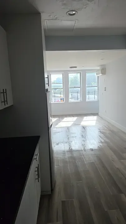 Freshly painted white hallway and kitchen with new wood flooring in a Bronx apartment