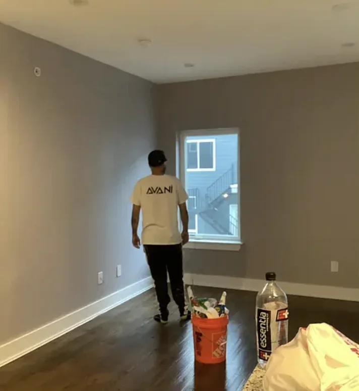 Painter working in a freshly repainted gray bedroom